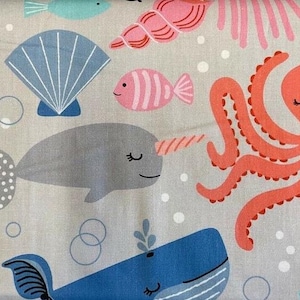 May include: A light gray fabric with a colorful sea life pattern. The pattern includes a pink and white striped fish, a gray narwhal, a blue whale, a pink and white seashell, a red octopus, and a blue jellyfish.