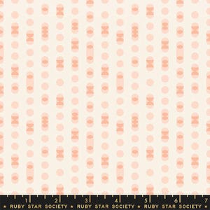 Può includere: Un tessuto bianco con un motivo ripetitivo di cerchi rosa e semicerchi rosa sovrapposti. Il tessuto ha una texture sottile e un righello con segni in pollici è visibile nella parte inferiore dell'immagine.