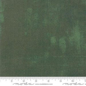 May include: A close-up of a dark green fabric with a subtle textured pattern. The fabric has a slightly distressed look, with faded areas and a hint of a lighter green color.