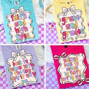 Può includere: Quattro magliette colorate con messaggi ispiratori. Le magliette sono azzurro, giallo, lavanda e rosa. Ogni maglietta ha un design unico con un fiocco e testo: "faith and high fives", "grace and grades", "back to school with the Holy Spirit with me" e "walking back to school by faith not by sight".