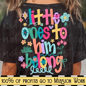 Op de afbeelding: Zwart T-shirt met de tekst "Little Ones To Him Belong" in kleurrijke, speelse letters. Het ontwerp bevat bloemen- en steraccenten. De onderkant van het shirt heeft de tekst "100% OF PROFITS GO TO MISSION WORK".