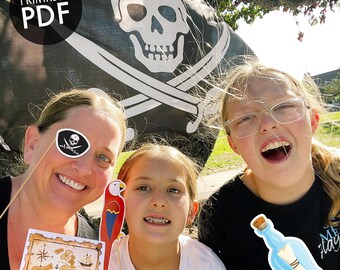 Puede incluir: Tres personas sonríen para una foto frente a una bandera pirata. La bandera es negra con una calavera y huesos cruzados blancos. Las personas sostienen accesorios de temática pirata, incluyendo un mapa del tesoro, un loro y una botella con un mensaje.