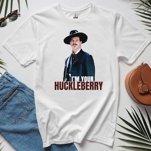 May include: White t-shirt with a printed image of a man wearing a hat and a dark suit. The text "I'm your Huckleberry" is printed below the image.
