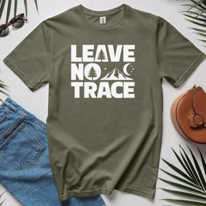 May include: A green t-shirt with the text "LEAVE NO TRACE" in white. The text is surrounded by a small tree, mountains, a crescent moon, and stars.