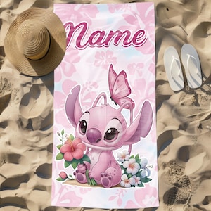 Pode incluir: Toalha de praia rosa com um personagem de desenho animado segurando flores, uma borboleta e a palavra "Name". A toalha tem um padr&atilde;o floral e est&aacute; na areia, ao lado de um chap&eacute;u de palha e chinelos brancos. A toalha tem cerca de 170 cm de comprimento.