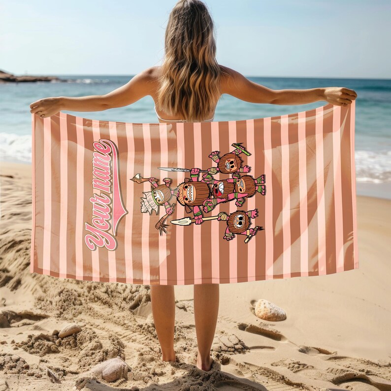 May include: A pink and brown striped beach towel with a cartoon illustration of a group of brown and pink characters holding spears. The text "Your Name" is written in a pink and white font on the towel.