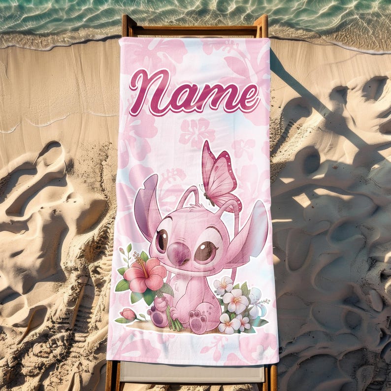 Pode incluir: Toalha de praia rosa com um personagem de desenho animado, uma borboleta e flores. A toalha tem a palavra "Name" em uma fonte cursiva. O fundo tem um padr&atilde;o floral. A toalha &eacute; exibida em uma cadeira de praia de madeira em uma praia arenosa.