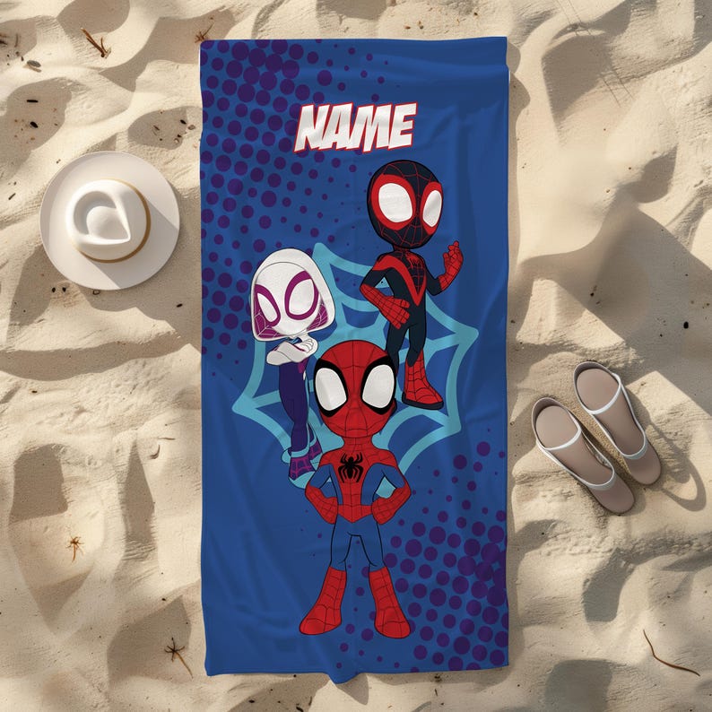 May include: Blue beach towel with cartoon Spider-Man characters. The towel has the word "NAME" at the top. The characters include Spider-Man, Spider-Gwen, and Miles Morales. The towel is on a sandy surface with a hat and sandals.
