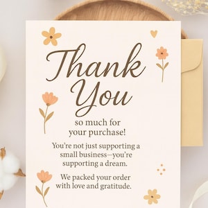 May include: A cream-colored thank you card with the words "Thank You" in a brown script font. The card is decorated with small orange flowers and the text "so much for your purchase!" and "We packed your order with love and gratitude."