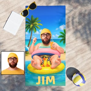 May include: Beach towel featuring a cartoon illustration of a man in a yellow swim ring with a duck, holding a drink. The towel has the name "JIM" in yellow letters. Yellow sunglasses and a volleyball are also visible.