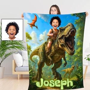 May include: A personalized blanket featuring a child riding a Tyrannosaurus Rex in a lush, green forest setting. The blanket has a vibrant illustration with a blue sky, orange pterodactyl, and the name "Joseph" in green.