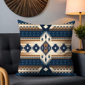 Puede incluir: Una almohada decorativa con un patrón geométrico en tonos azules, marrones y blancos. El patrón recuerda a los diseños de los nativos americanos.