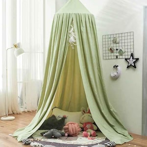 May include: A light green canopy bed with draped fabric, creating a cozy space. Inside, there are plush toys and pillows on a patterned rug. The canopy is suspended from the ceiling, offering a whimsical touch to a child's room.