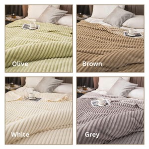 May include: A set of four plush blankets in olive, brown, white, and grey. Each blanket is displayed on a bed with a pillow and a cup and saucer. The blankets have a ribbed texture and the color name is displayed on each blanket.