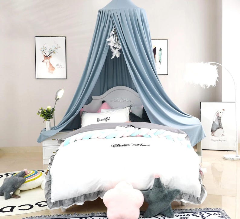 May include: A light blue canopy bed with a white comforter set. The comforter has the text "Cheshire Moore" on it. Decorative pillows and artwork of a deer and a rabbit are also present.