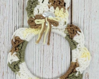 May include: Crocheted dish towel ring in brown, green, and white with a shell button and a bow.