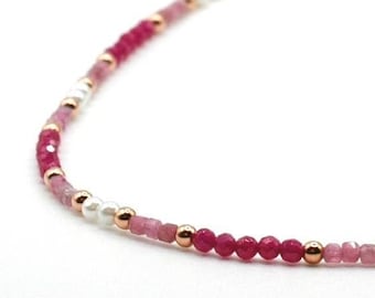 May include: A delicate beaded necklace featuring a repeating pattern of faceted deep pink and light pink gemstone beads, small white pearls, and polished gold-tone metal spacer beads arranged in a continuous circular strand on a thin cord.