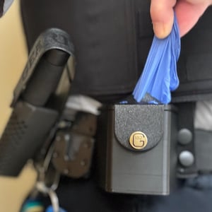 May include: A black utility belt with a black pouch and a blue glove. The pouch has a gold metal logo with the letters "BG".