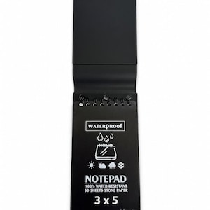 Könnte beinhalten: Ein schwarzer Notizblock mit Klappdeckel und Spiralbindung. Auf dem Notizblock steht das Wort "WATERPROOF" oben. Der Notizblock ist 7,6 x 12,7 cm groß und trägt den Text "NOTEPAD" und "100% WATER-RESISTANT 50 SHEETS STONE PAPER".