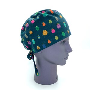 May include: A dark green scrub hat with a colorful beetle pattern. The hat has a tie on the back.