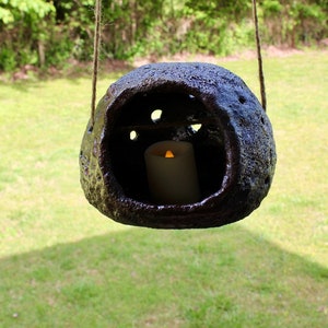 K&ouml;nnte beinhalten: Eine dunkelbraune, h&auml;ngende Keramiklaterne mit einer Kerze im Inneren. Die Laterne hat eine raue, strukturierte Oberfl&auml;che und h&auml;ngt an einer Schnur.