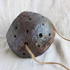 K&ouml;nnte beinhalten: Ein dunkelgrauer Keramiktopf mit einer rauen, strukturierten Oberfl&auml;che und einem Seilgriff. Der Topf hat viele kleine L&ouml;cher &uuml;ber die gesamte Oberfl&auml;che.