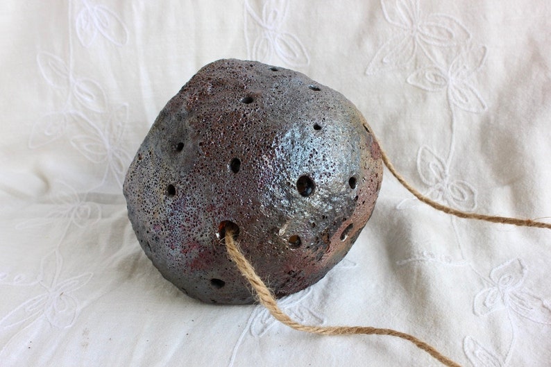 K&ouml;nnte beinhalten: Ein dunkelgrauer Keramiktopf mit einer rauen, strukturierten Oberfl&auml;che und einem Seilgriff. Der Topf hat viele kleine L&ouml;cher &uuml;ber die gesamte Oberfl&auml;che.