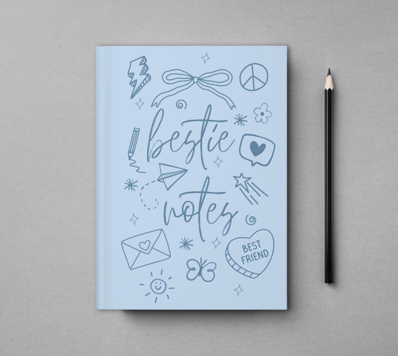 May include: A light blue notebook with the words "bestie notes" in cursive, surrounded by doodles. A black pencil rests beside the notebook on a gray surface. The notebook features a heart-shaped design that says "Best Friend".