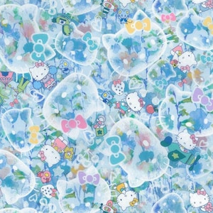 以下が含まれることがあります： リボンが付いた漫画のキャラクターが繰り返しデザインされた青と白のパターンファブリック。キャラクターはハート、星、リボンで囲まれています