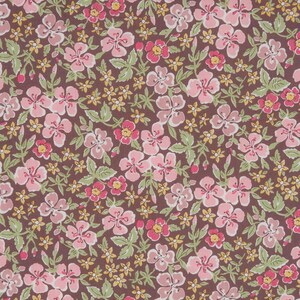 Könnte beinhalten: Nahaufnahme eines floralen Stoffes mit braunem Hintergrund. Das Muster zeigt rosa und rote Blüten mit gelben Zentren, umgeben von grünen Blättern und kleineren gelben Blüten. Das Design ist ein sich wiederholendes Blumenmuster.