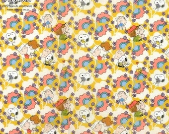 Può includere: Un motivo ripetuto con Snoopy, Charlie Brown e altri personaggi dei Peanuts, su sfondo giallo con accenti floreali rosa e blu. Il testo "Vintage Peanuts" è visibile in alto a sinistra.