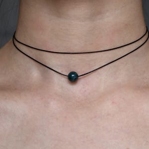 Könnte beinhalten: Eine einfache Choker-Kette mit einer dunkelgrünen Edelsteinperle.