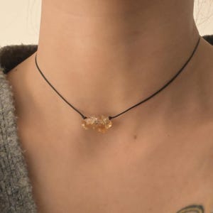 以下が含まれることがあります： 黒い紐にシンプルなゴールドクリスタルネックレス