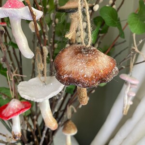 four clay glittery mushroom ornament  hanging on branches background