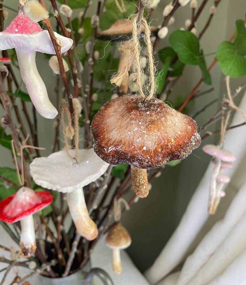 four clay glittery mushroom ornament  hanging on branches background