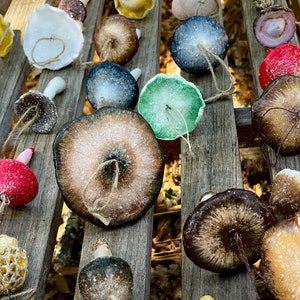 mushroom ornaments in many colors laying down on brown bench, sparkling