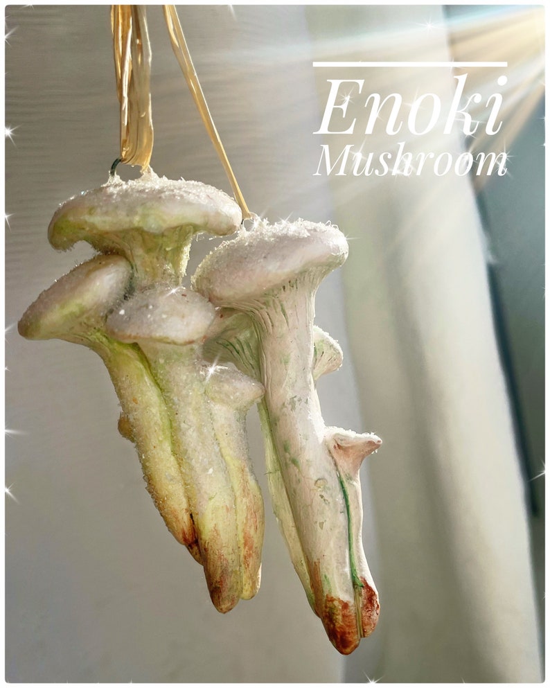 pink and white clay glittery mushroom ornament hanging from string, curtain in background, sun streaming from window