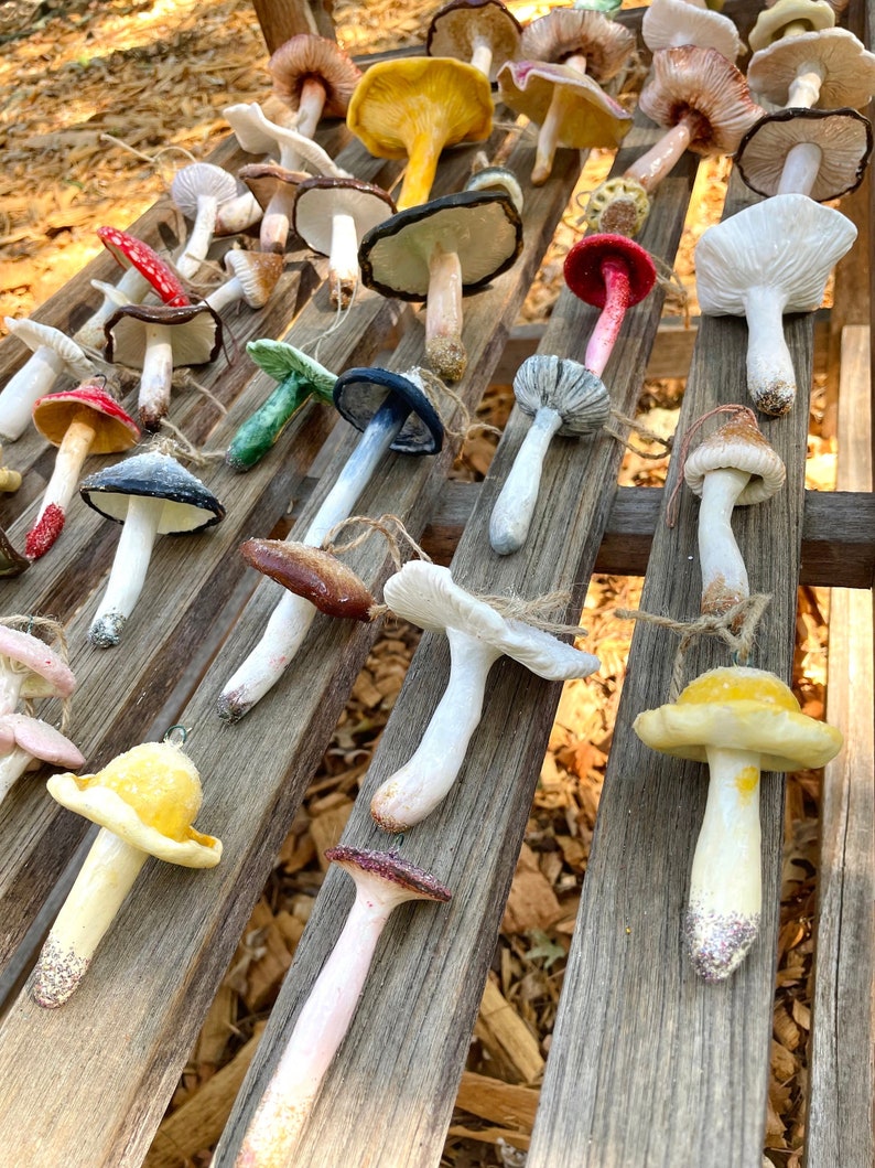 mushroom ornaments in many colors laying down on brown bench, sparkling
