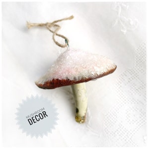 one pink and white clay glittery mushroom ornament  laying on lace white background