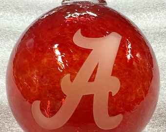 May include: Red glass Christmas ornament with a white frosted "A" etched on the front.