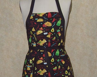 Pode incluir: Avental preto com um padrão colorido com tema de festa. O design inclui tacos, abacates, pimentas e garrafas de salsa. O avental tem uma alça de pescoço e uma faixa na cintura pretas. As palavras "Fiesta Time" e "Hot & Spicy" são visíveis.