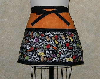 Pode incluir: Avental preto e laranja com uma estampa em preto e branco de várias frutas, vegetais e texto que diz "ovos frescos", "comprar local", "mercado de agricultores" e "orgânico".