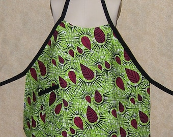 Pode incluir: Um avental verde e bordô com um padrão de folhas. O avental tem uma alça ajustável preta e um bolso preto.