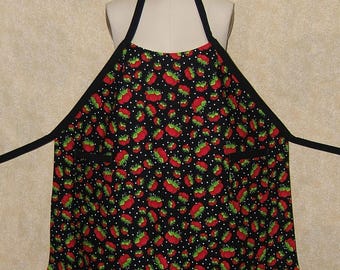 Pode incluir: Um avental preto com padrão de bolinhas brancas e estampa de morango vermelho. O avental tem alças ajustáveis e dois bolsos.