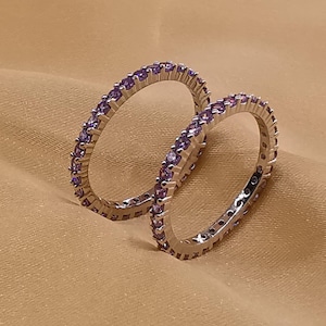 May include: Two silver rings with a row of small purple gemstones around the band.