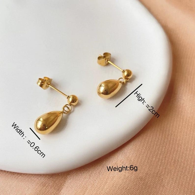 Op de afbeelding: Een paar gouden oorhangers met een druppelvorm. De oorhangers zijn ongeveer 2 cm lang en 0,6 cm breed. Gewicht: 6 gram.
