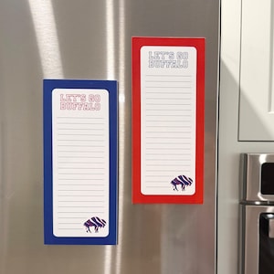 May include: Two rectangular notepads with the text "LET'S GO BUFFALO". One notepad is blue with a white interior, and the other is red with a white interior. Each notepad has a buffalo logo at the bottom.