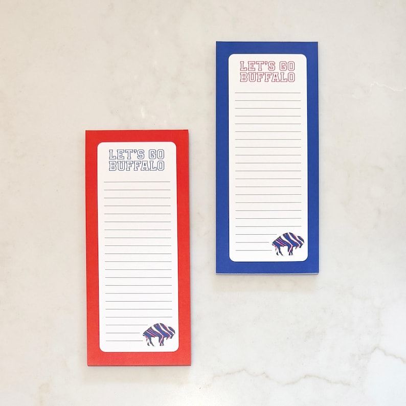 May include: Two rectangular notepads, one red and one blue, with the text "LET'S GO BUFFALO" at the top. Each notepad has lined paper and a buffalo logo at the bottom. The red notepad is smaller than the blue one.
