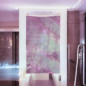Könnte beinhalten: Eine Wandteppich mit einem abstrakten Design in Rosa, Weiß und Grün. Der Wandteppich hat einen abgenutzten, Vintage-Look und hängt an einer Wand in einem Raum mit modernem Design.
