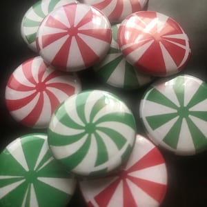 May include: A collection of red and green peppermint swirl patterned buttons. The buttons are round and have a glossy finish.